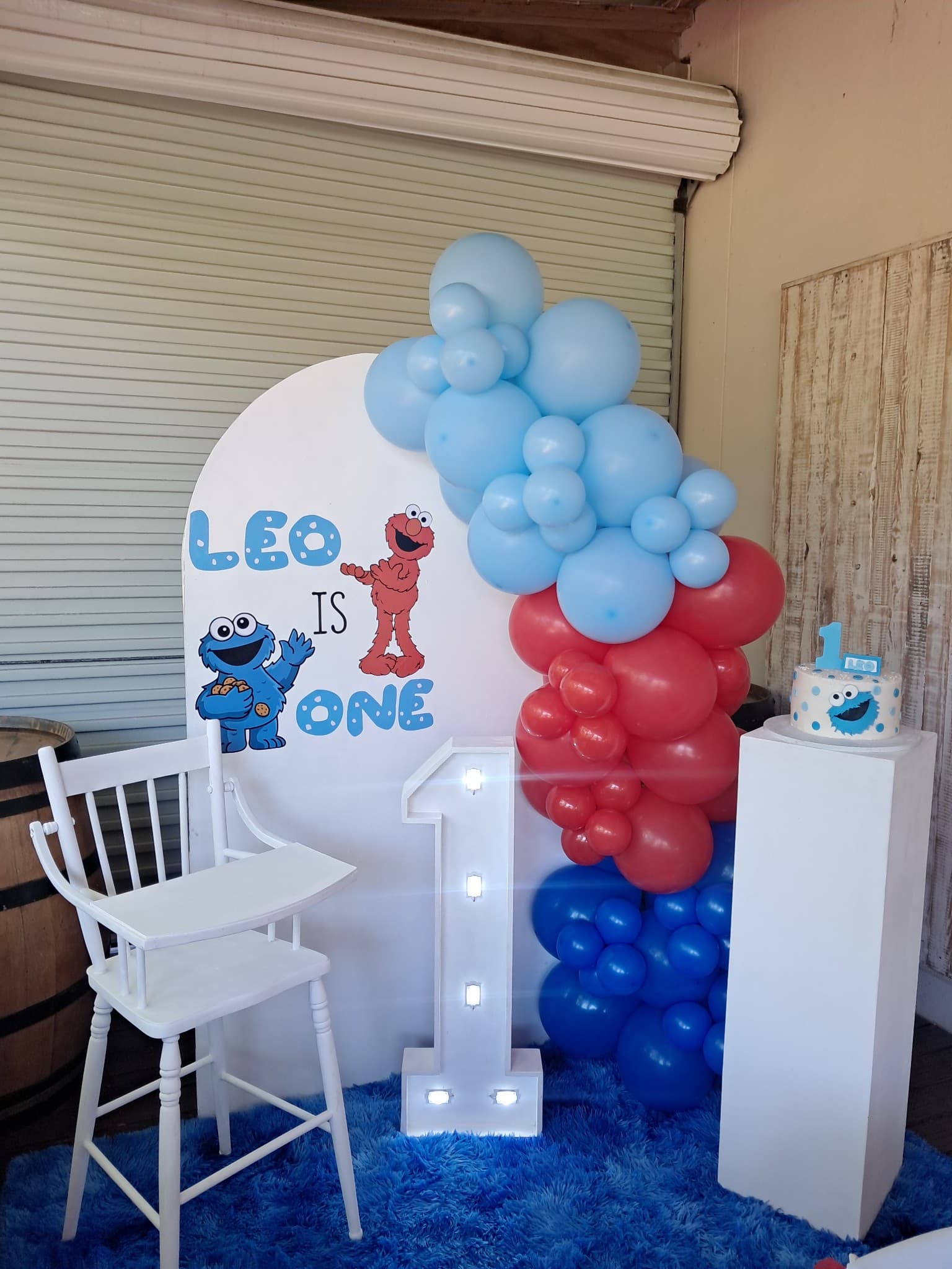 Sesame Street birthday party backdrop with light-up number and Cookie Monster cake