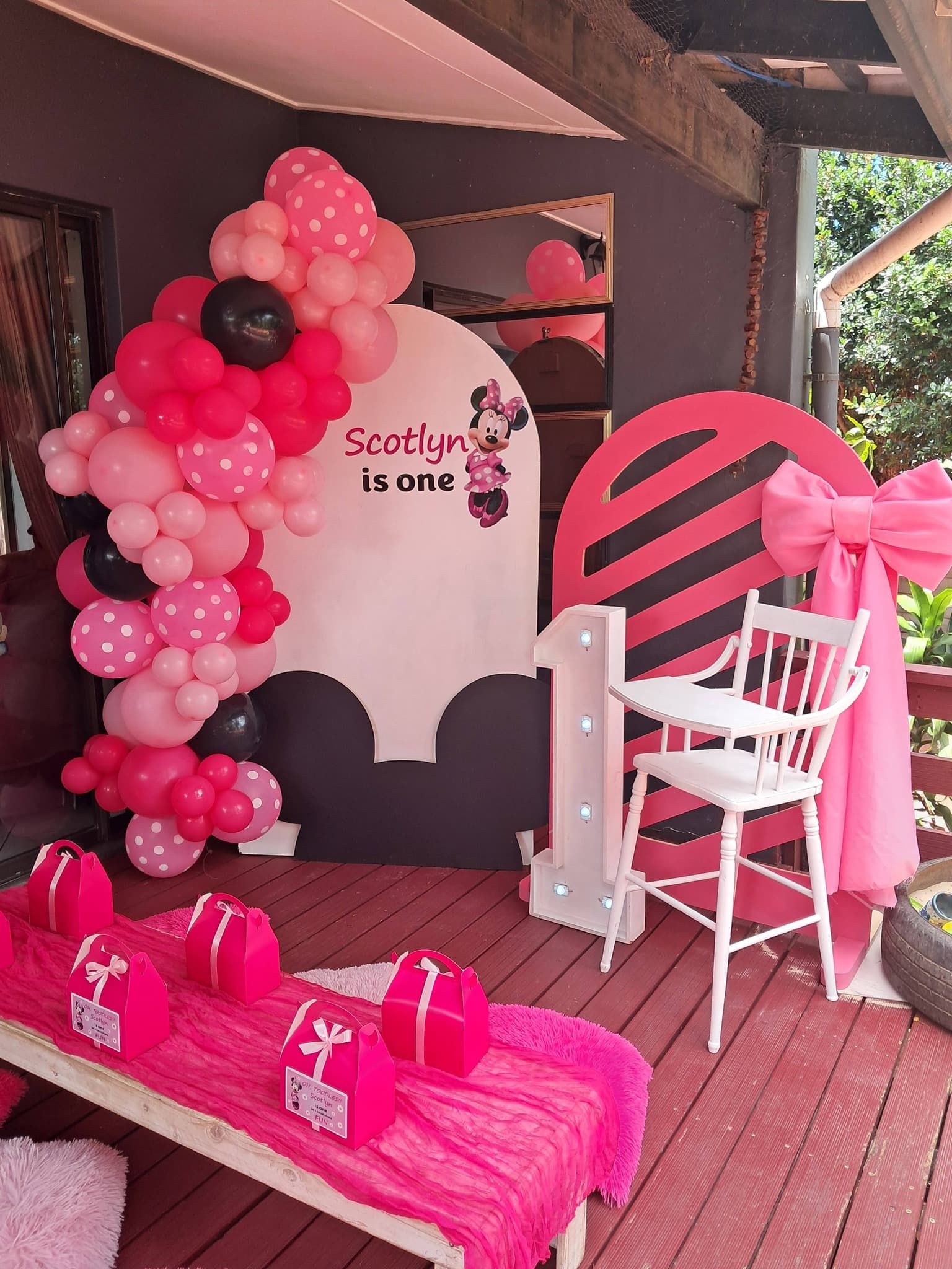 Minnie Mouse themed party with pink balloon arch and Scotlyn is One backdrop