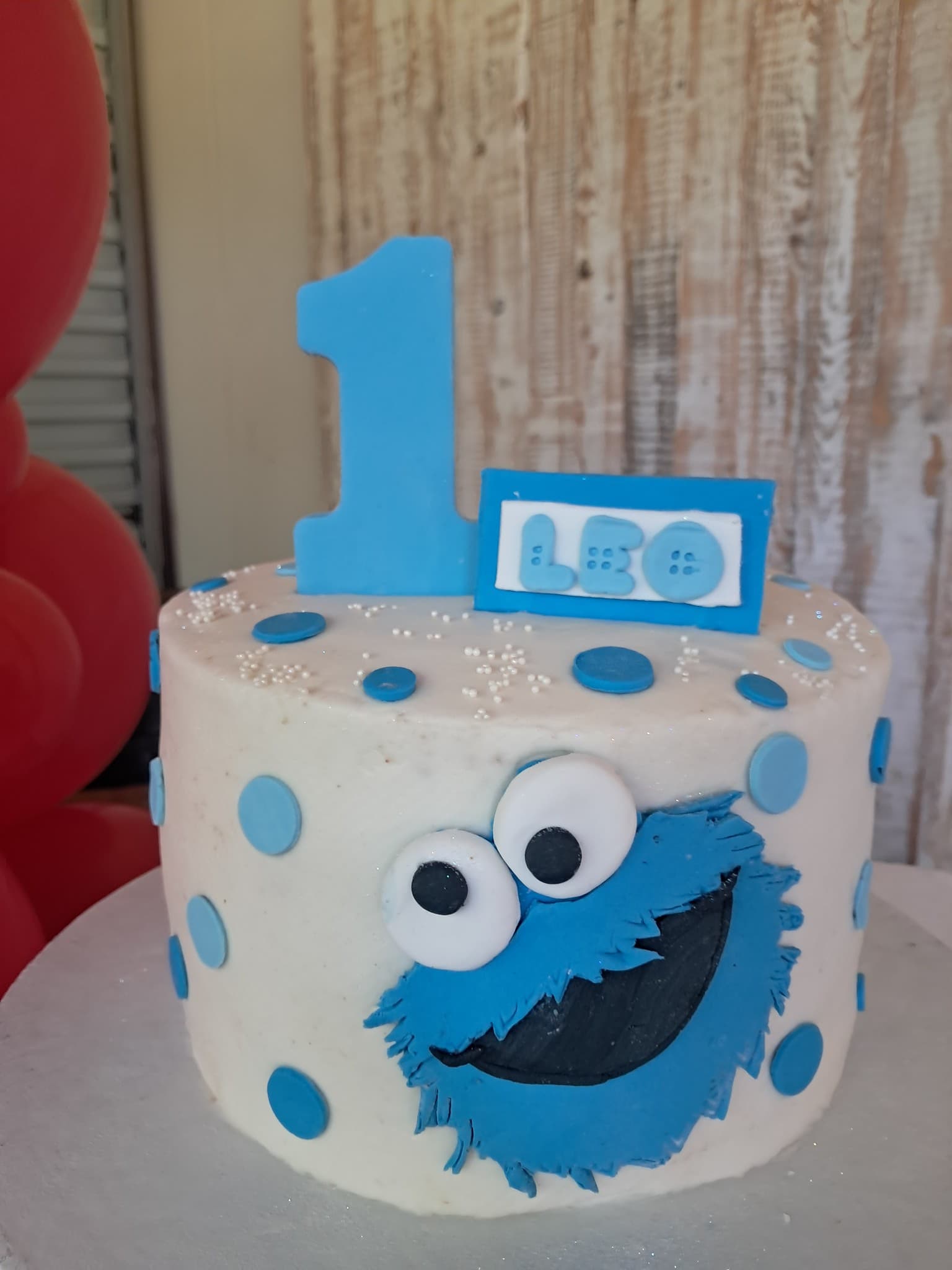 Cookie Monster themed birthday cake with blue polka dots and number 1 topper