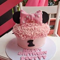 Pink Minnie Mouse birthday cake with ruffles and bow
